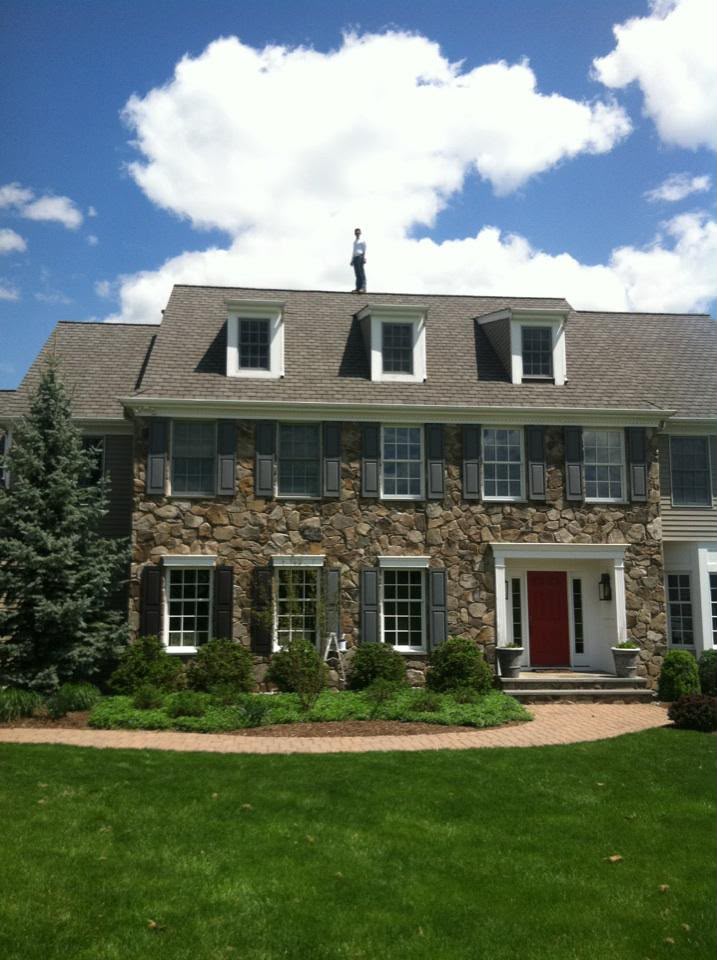 Wide view of the stone Colonial and front lawn