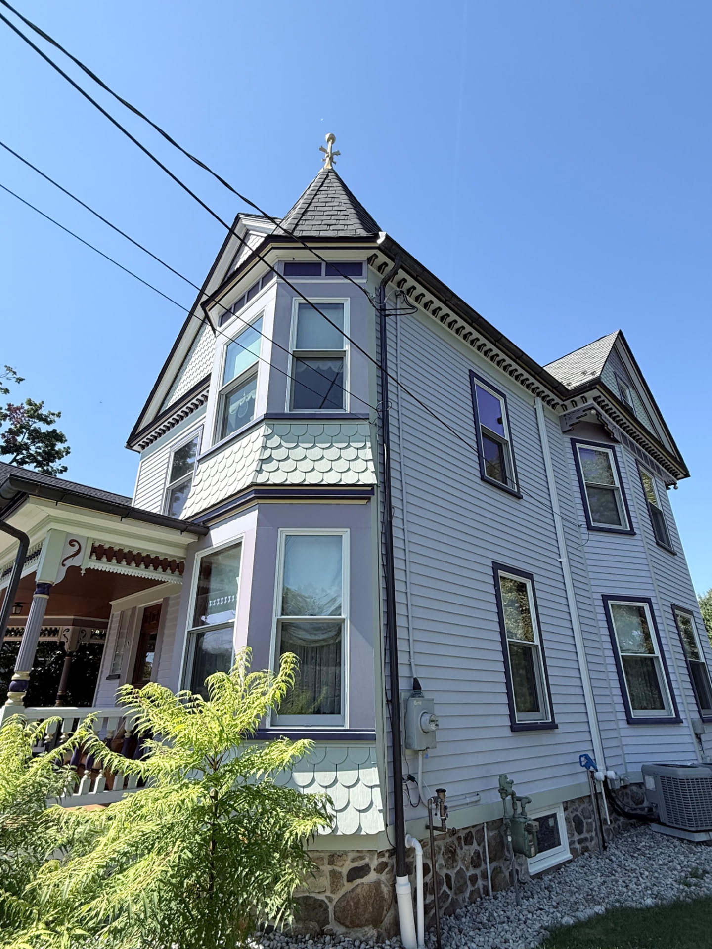 Turret with mint fish-scale shingles, lavender bay windows and purple casings
