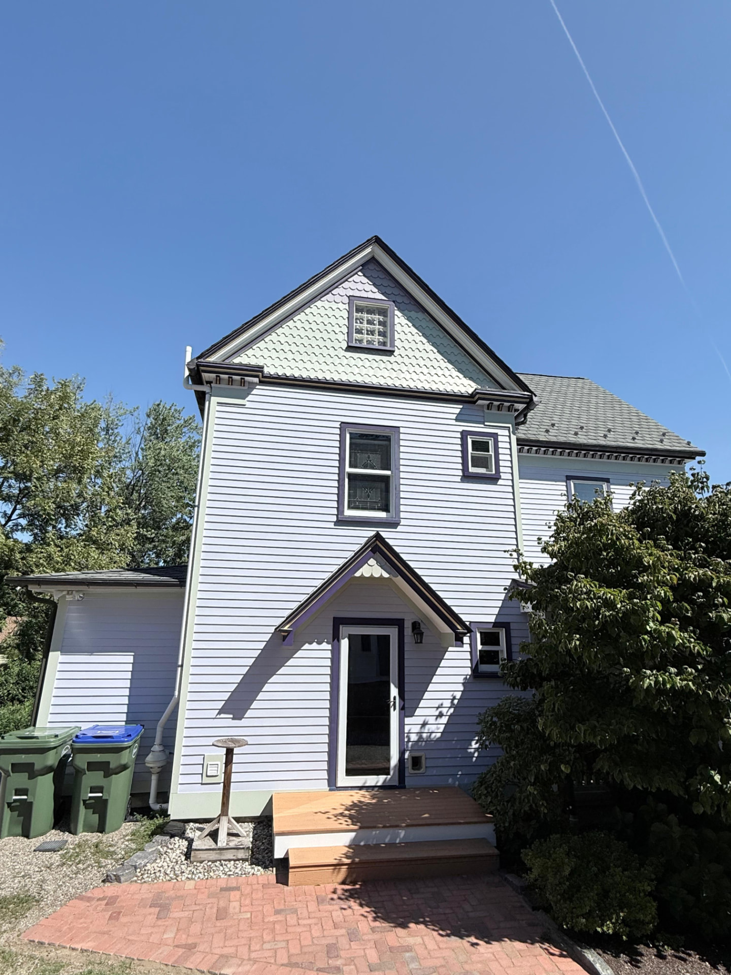 Rear gable with fish-scale shingles and a painted entry hood over the back door
