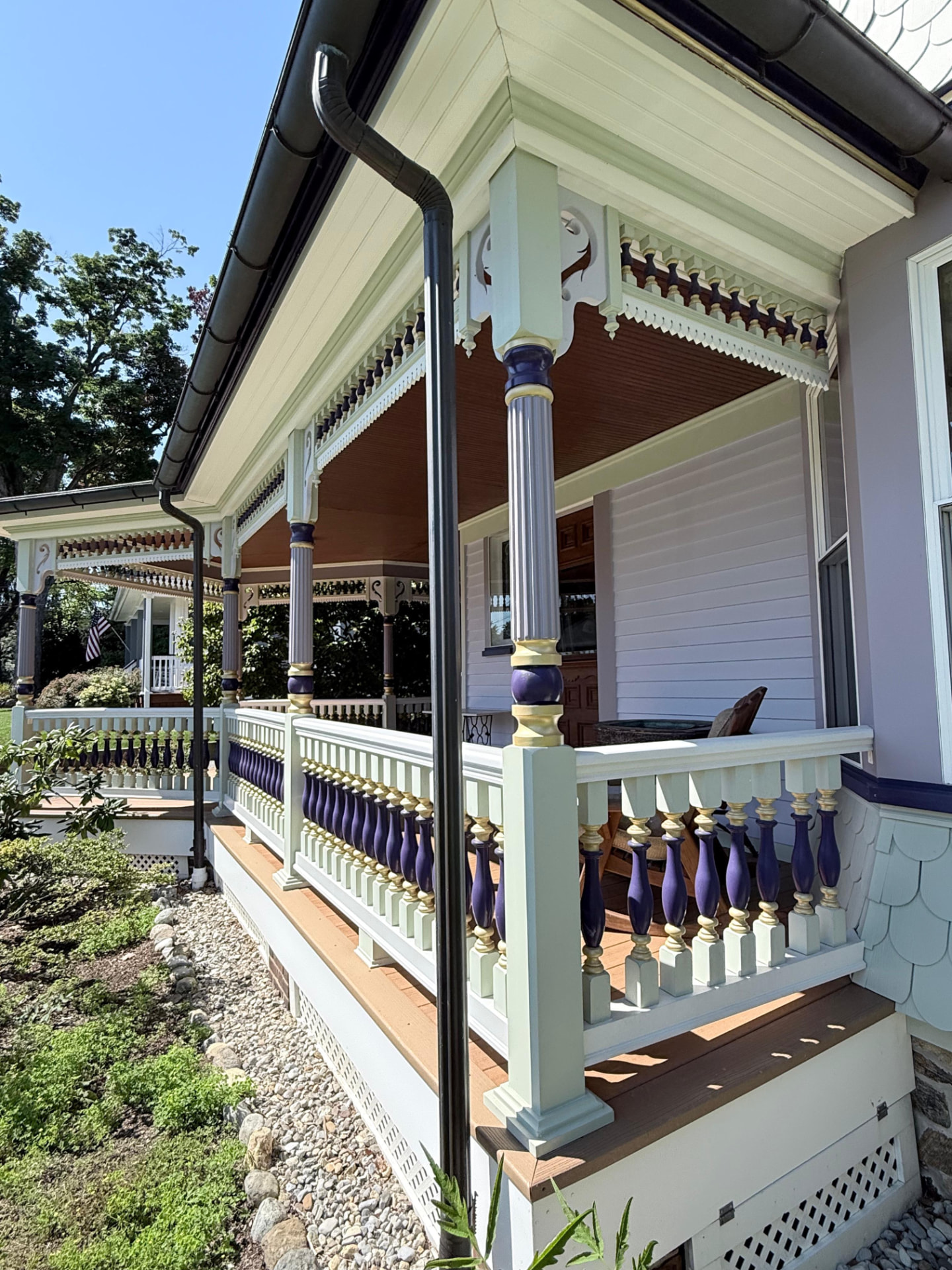 Wraparound porch with purple and gold turned balusters and fluted columns