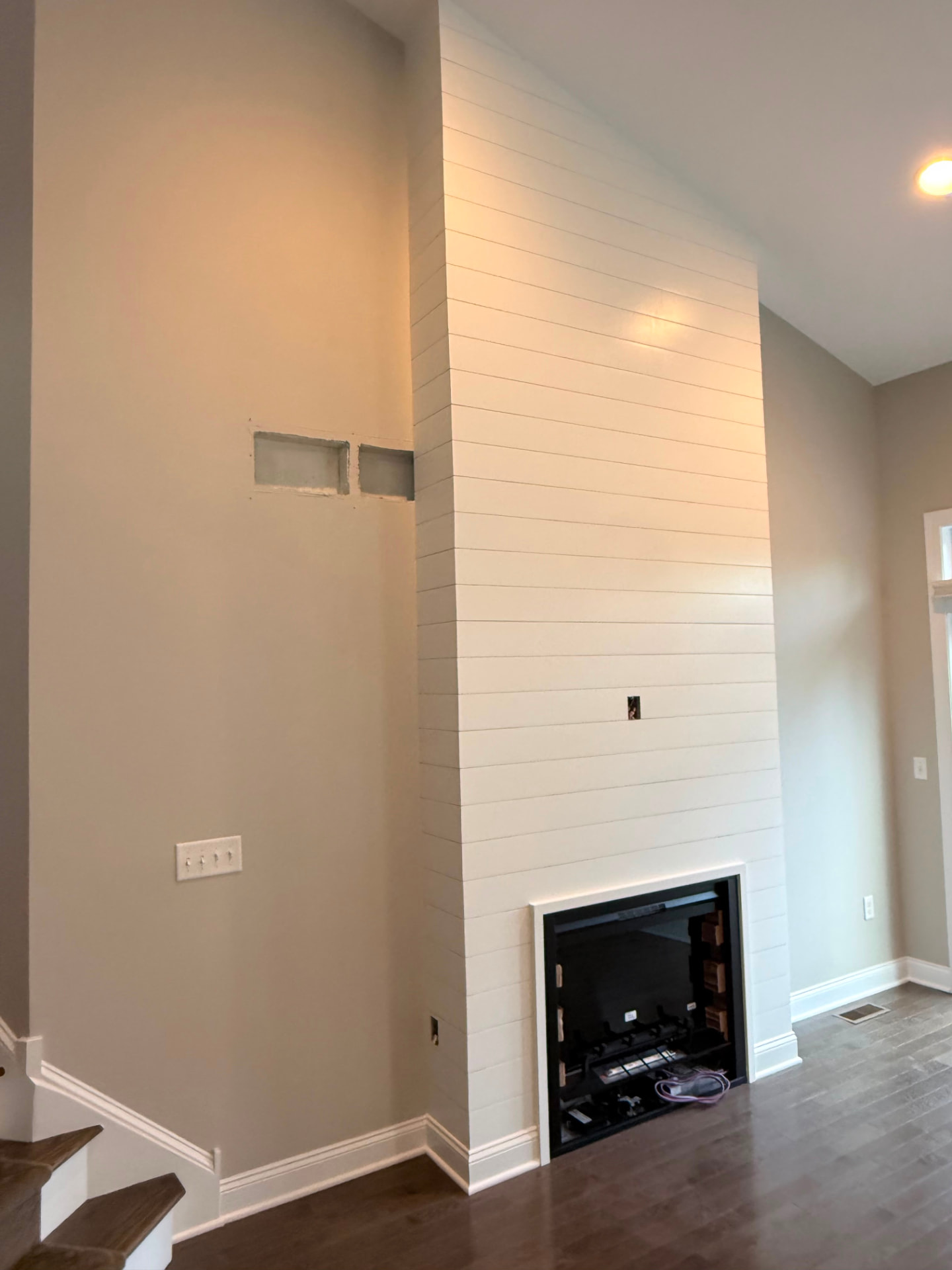 Angled view of the shiplap fireplace wall next to the staircase