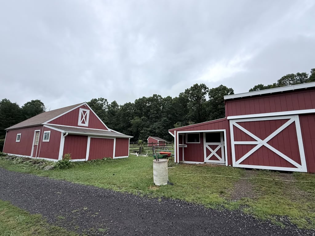 Barn and stable both painted red with white trim and X-braced doors