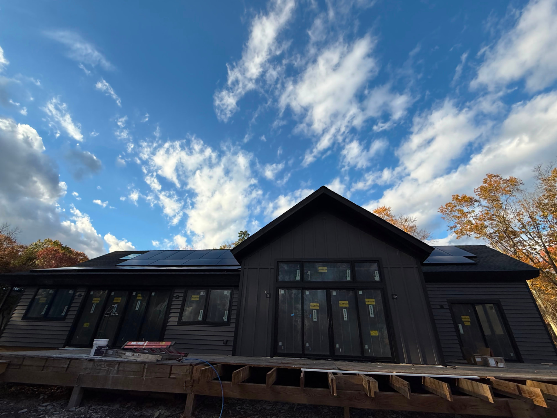 Wide view of the charcoal home with solar panels and large rear windows