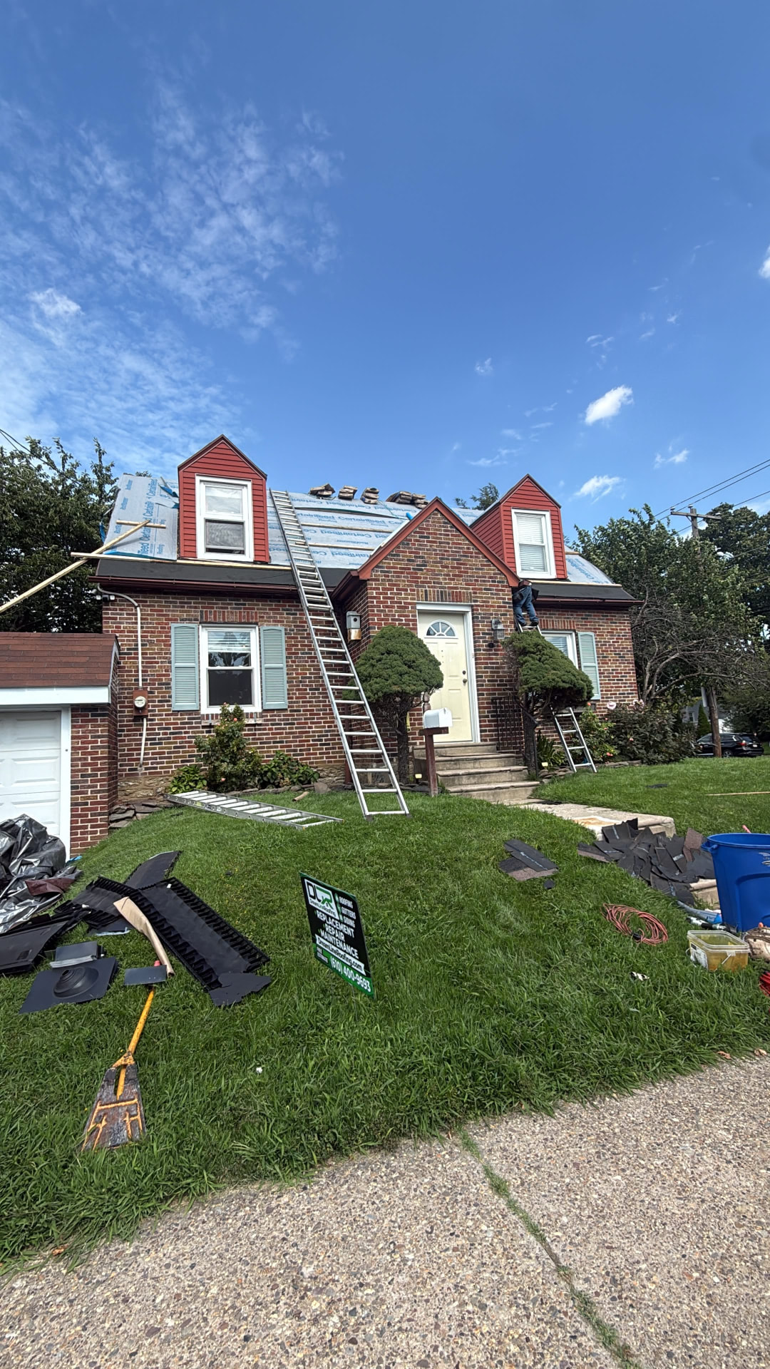 Brick Cape Cod home with new synthetic underlayment on the roof and ladders in place