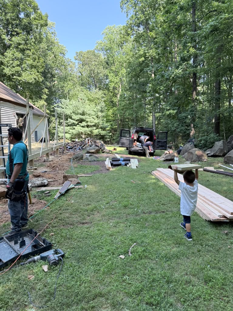 Crew unloading lumber and setting up beside the house to start the porch