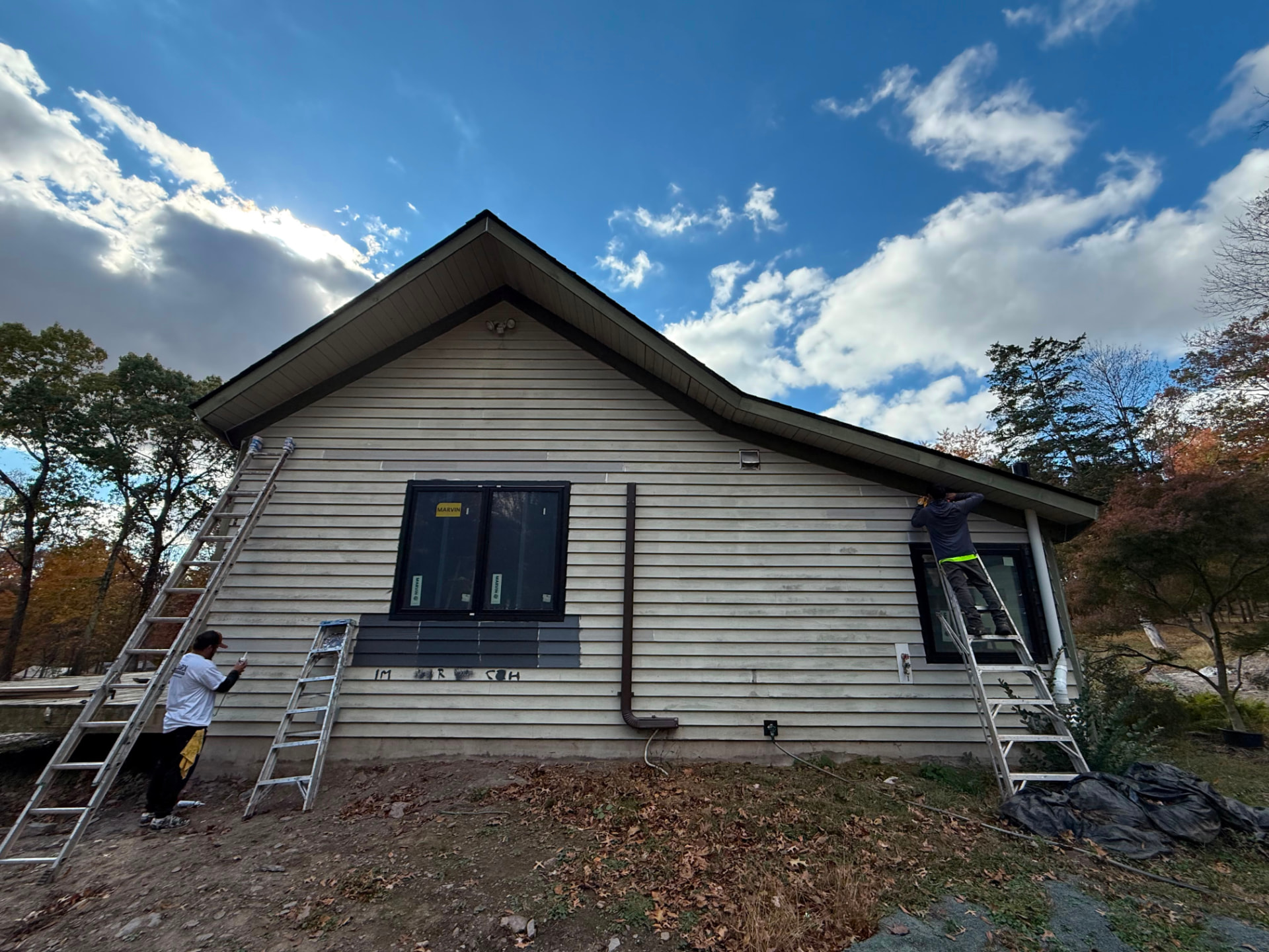 Painters on ladders painting the gable end of the house