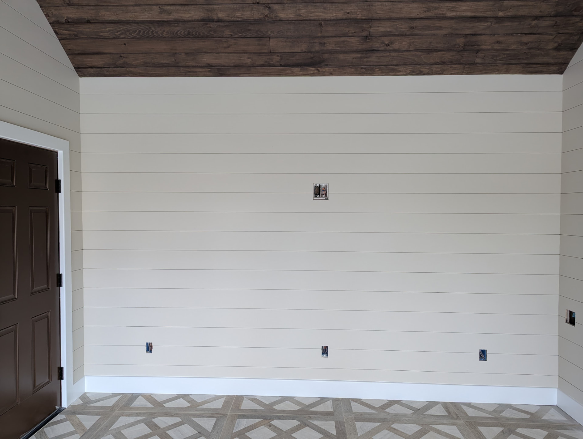 Shiplap wall beside a brown six-panel door with white casing