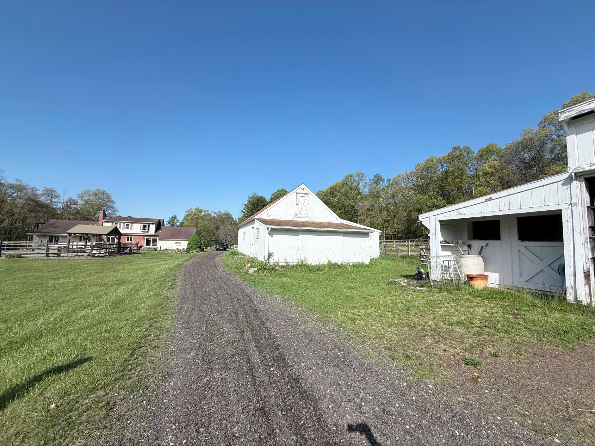 Farm driveway with weathered white barns before painting