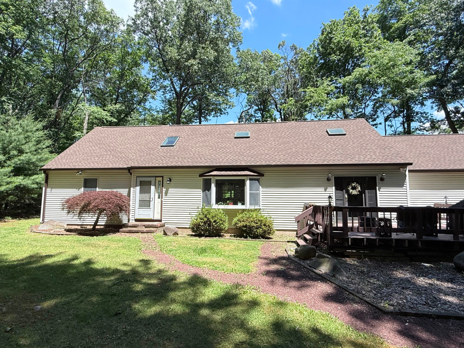 Cape Cod home before the porch with a small raised deck and flat roofline