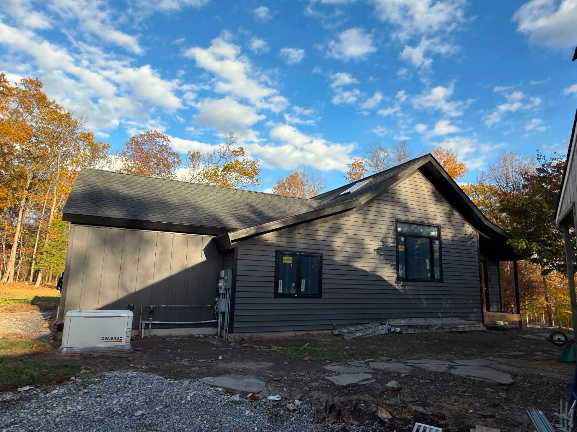 Side of the home painted deep charcoal under a blue sky