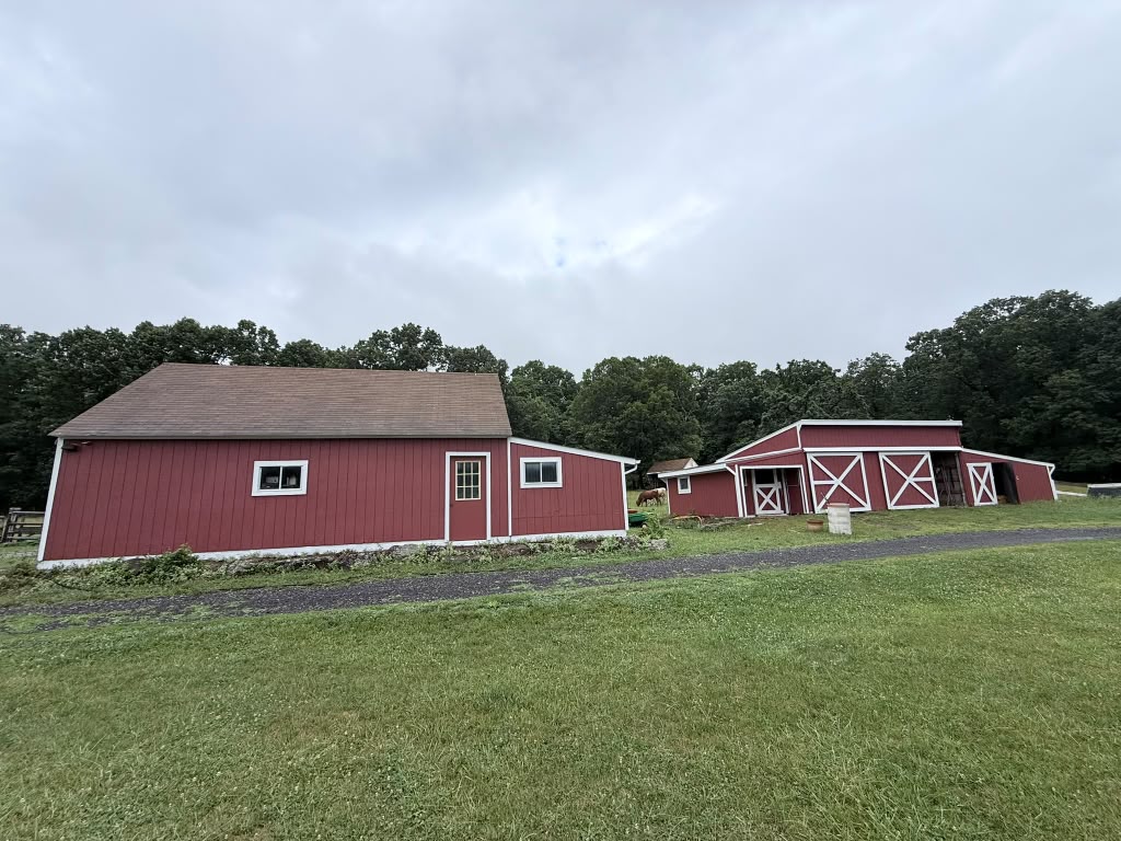 Long side of the red barn with the red stable beyond