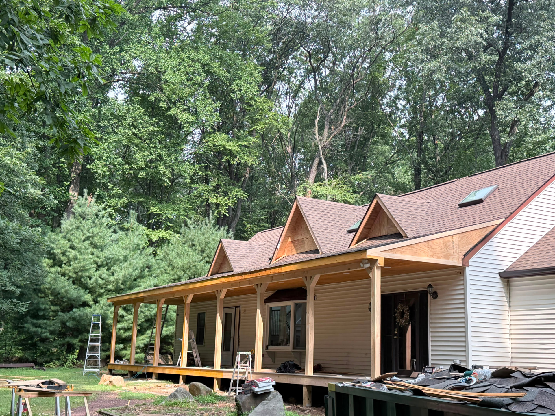 Porch framed with timber posts and new dormers sheathed in plywood