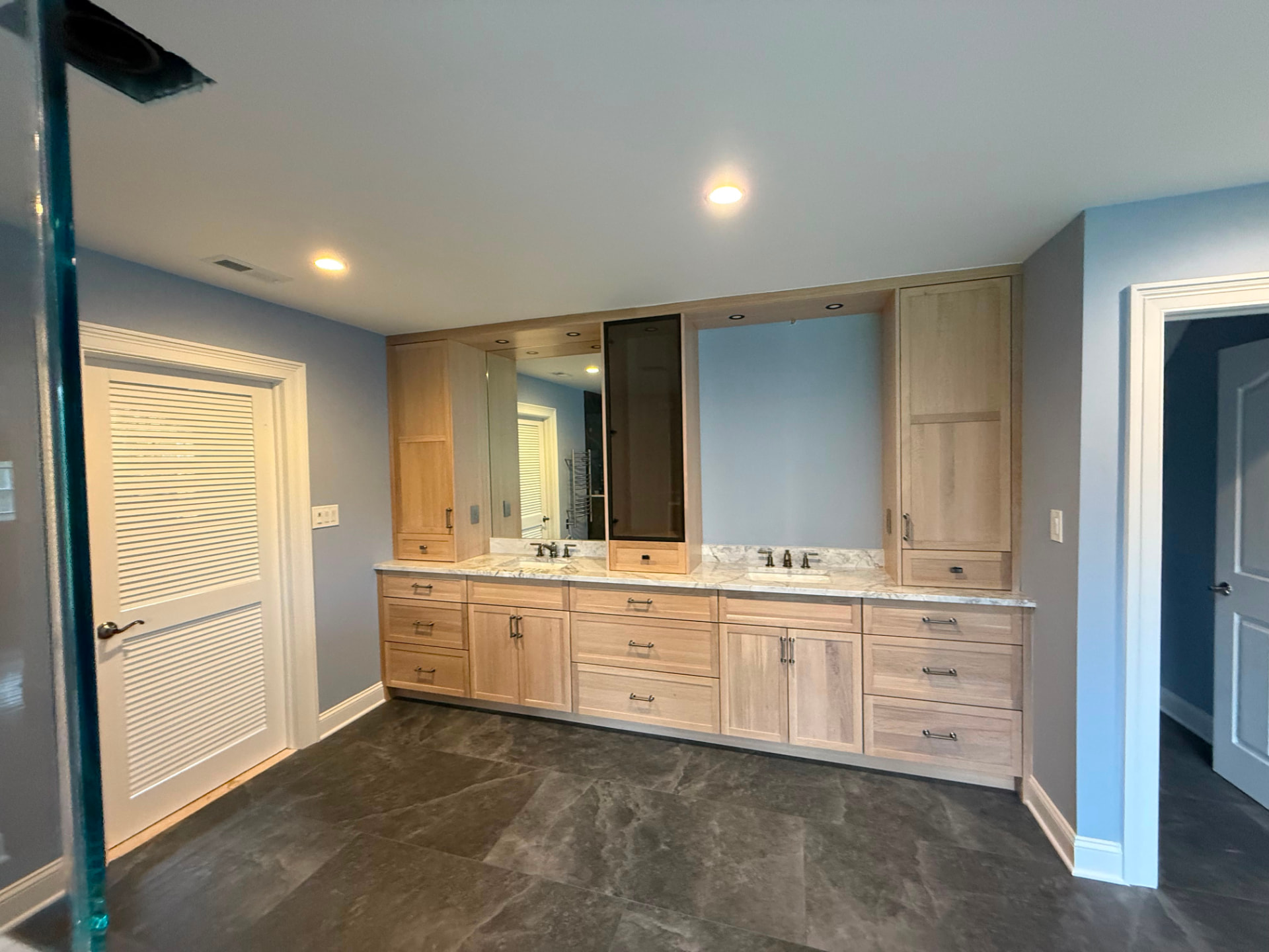 Light wood double vanity against freshly painted blue-gray walls