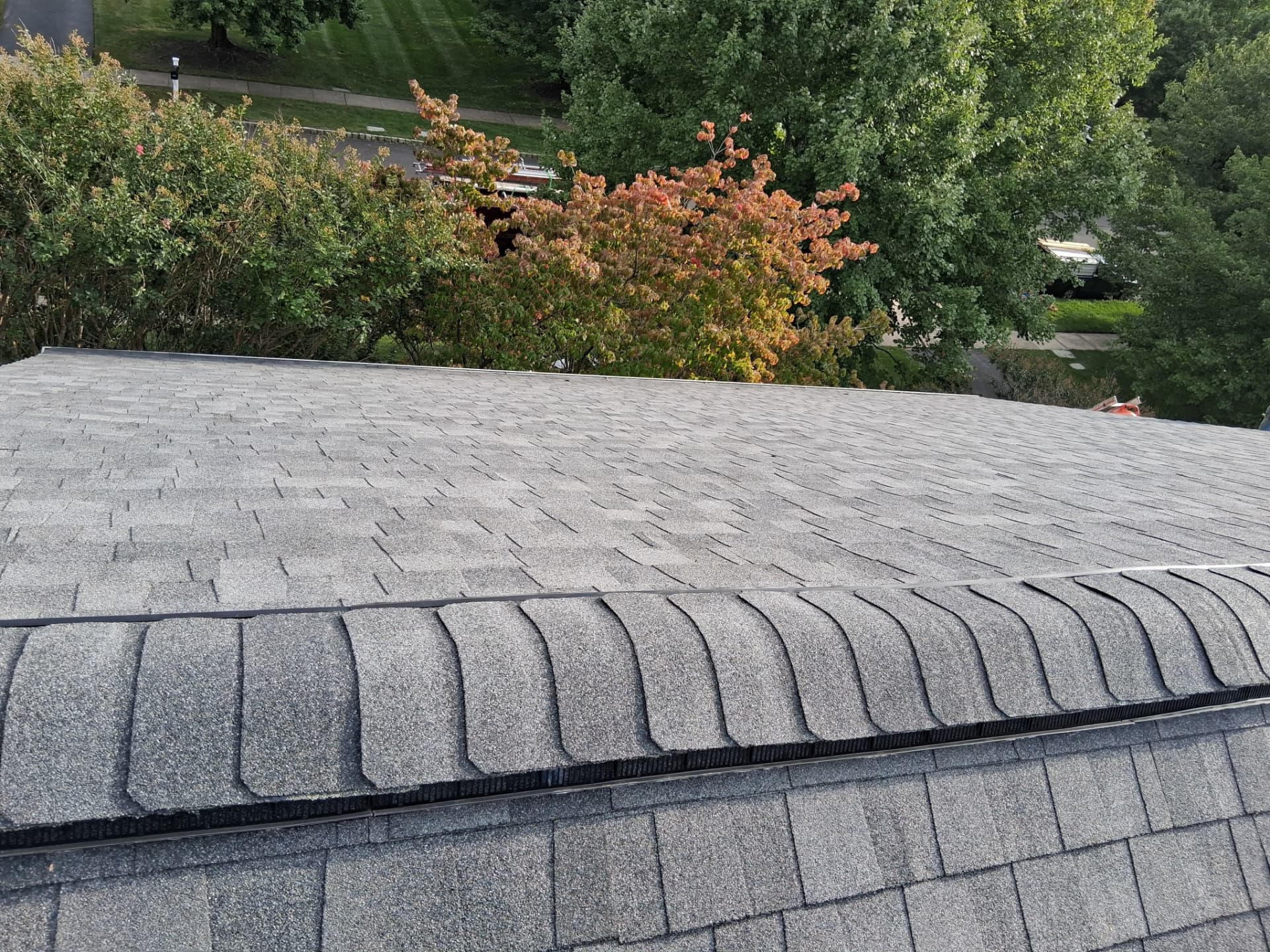 Close view of a new shingle-over ridge vent on a gray asphalt roof