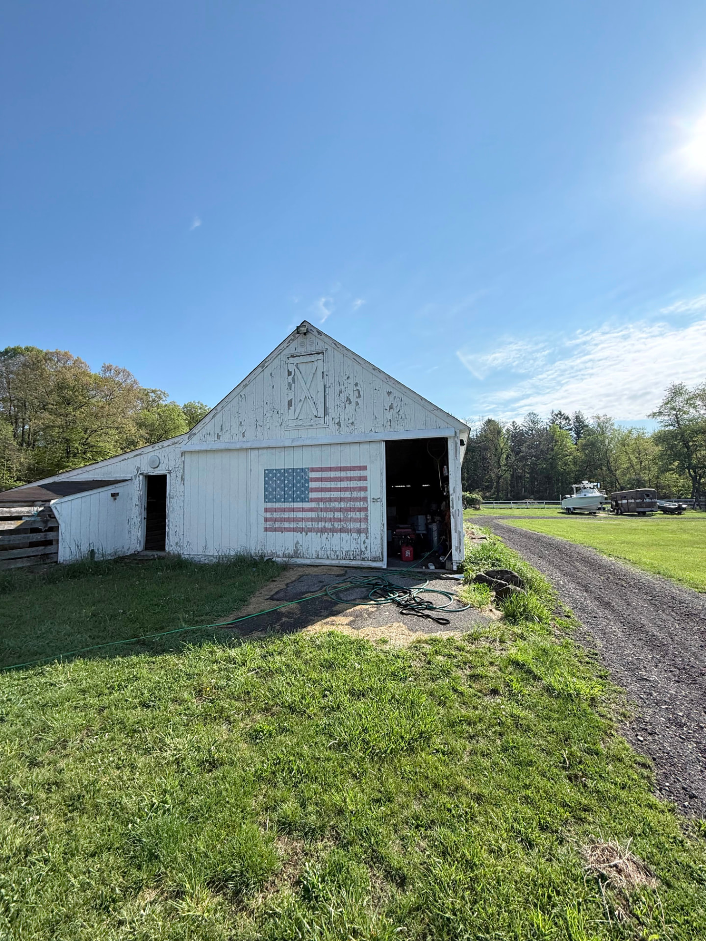 White barn with heavily peeling paint and painted flag before the work