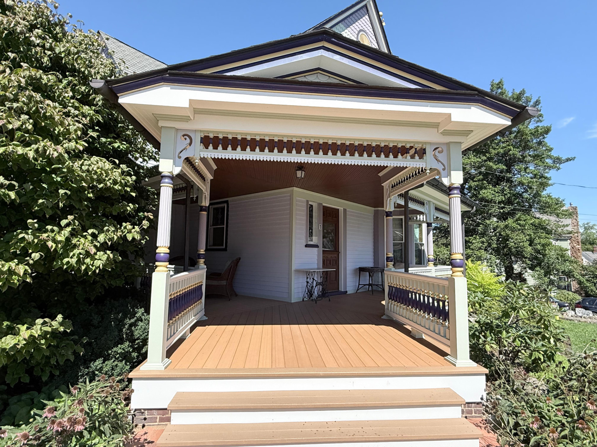 Corner porch pavilion with painted spindlework frieze, scroll brackets and fluted columns
