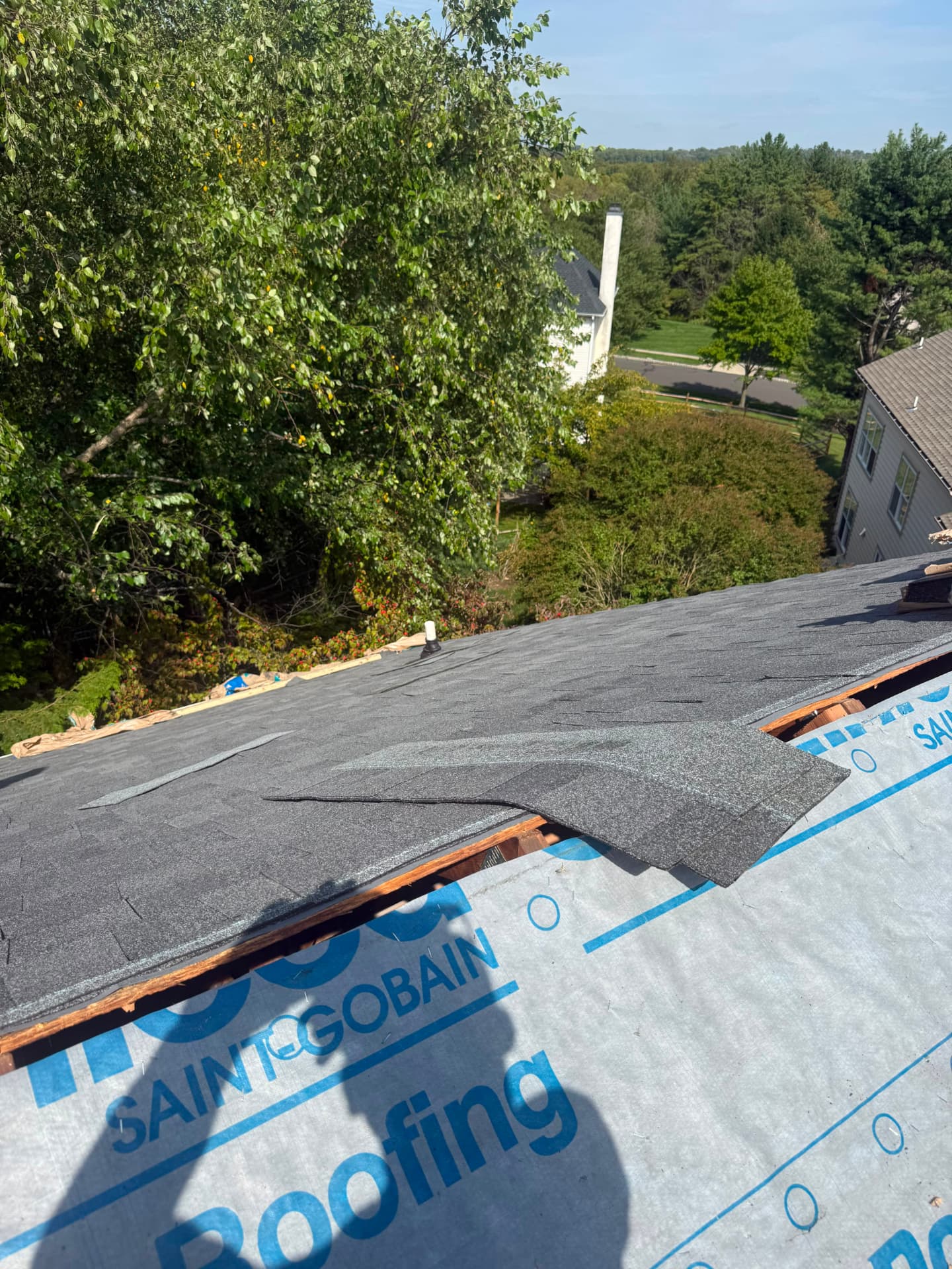 Partially installed shingle roof next to exposed underlayment during a roof replacement