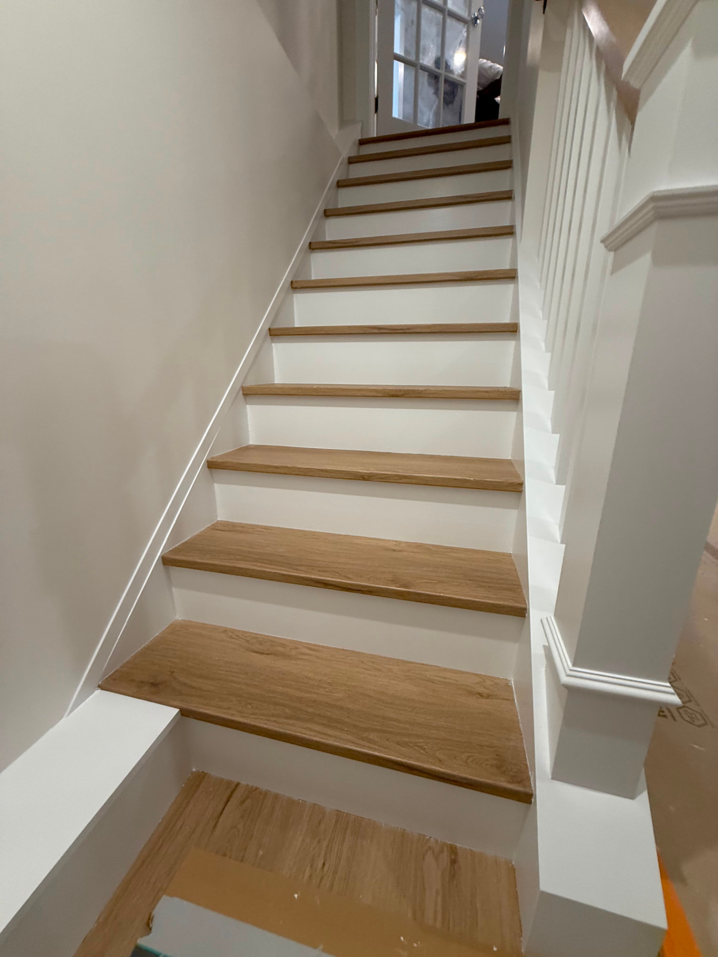 Close view of the stair with crisp white risers and paneled wall trim