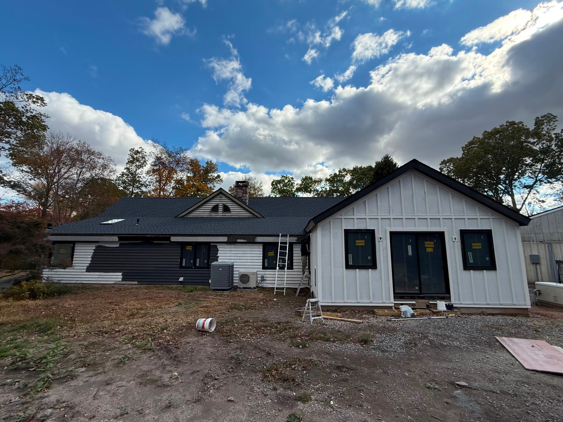 House partway through painting, with some siding dark and some still light