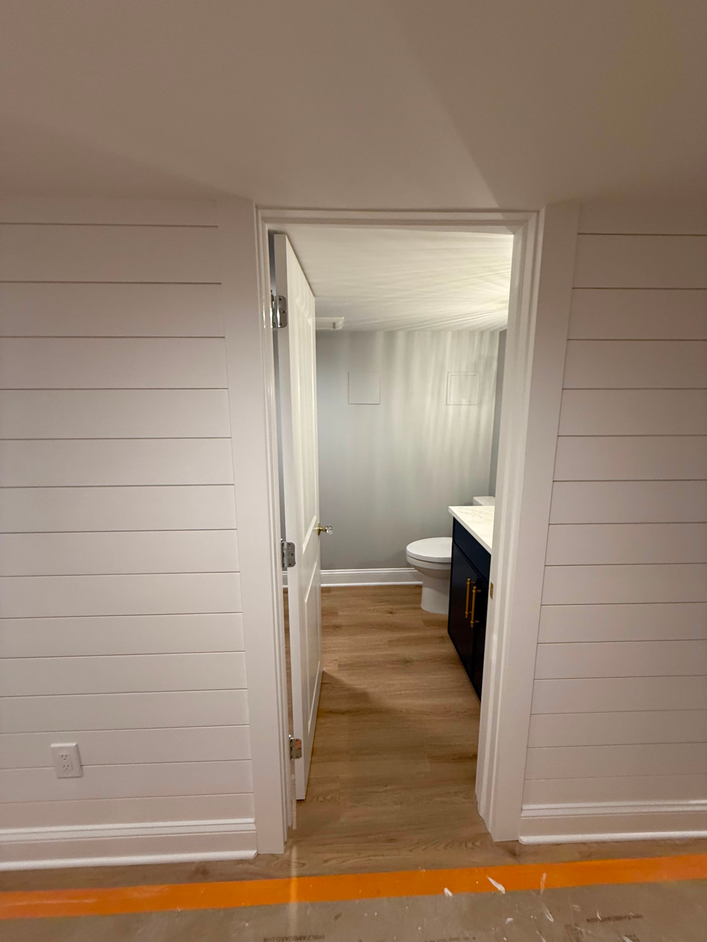 Shiplap wall and painted door casing opening into the powder room
