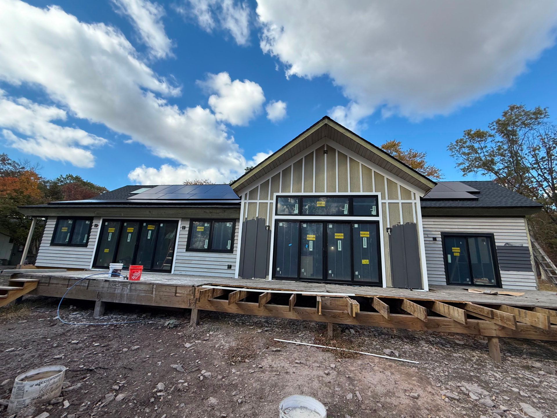 Rear of the Pittstown home with pale siding before painting, deck framing in front