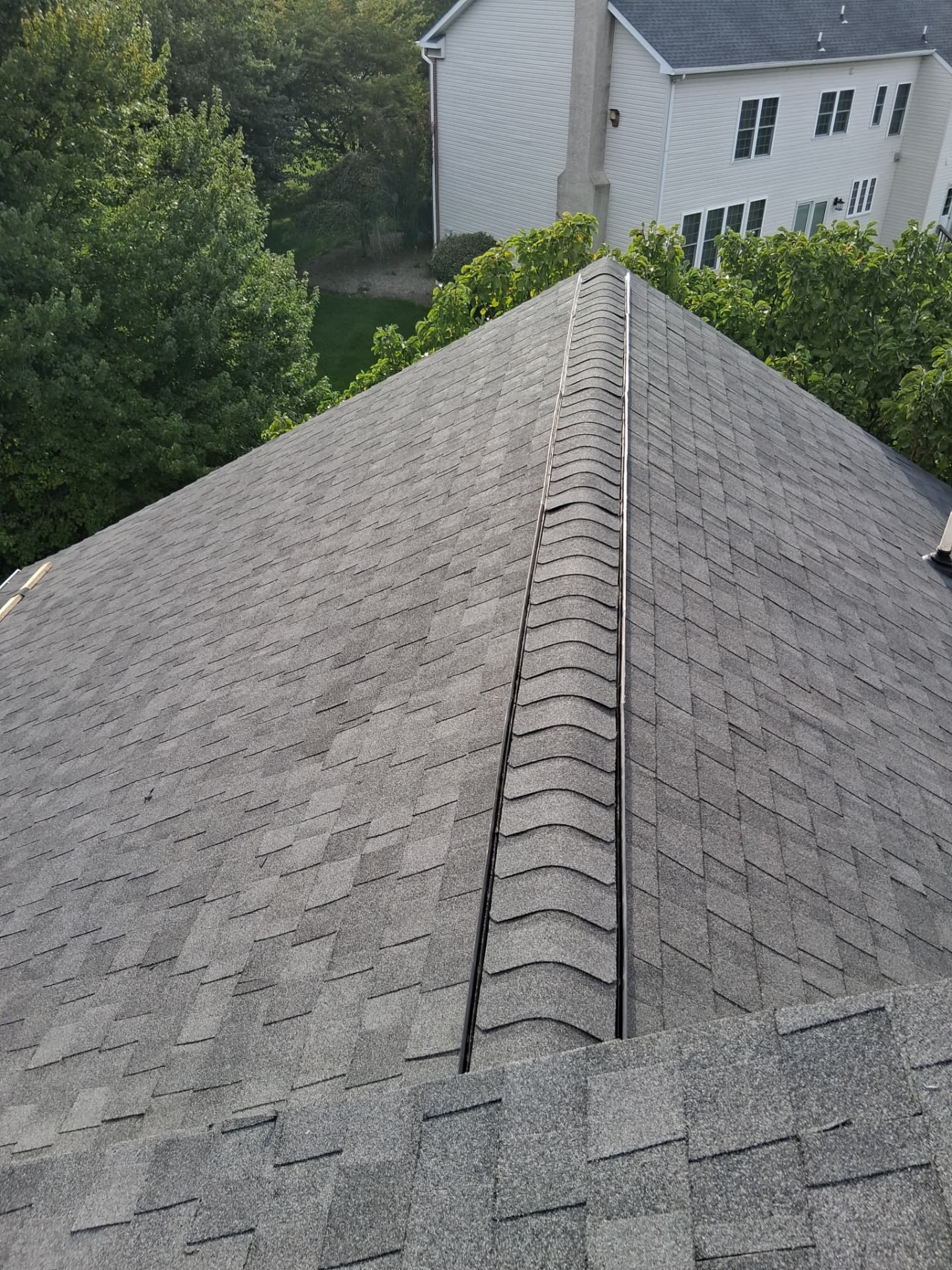 New hip ridge cap shingles running up a gray architectural shingle roof
